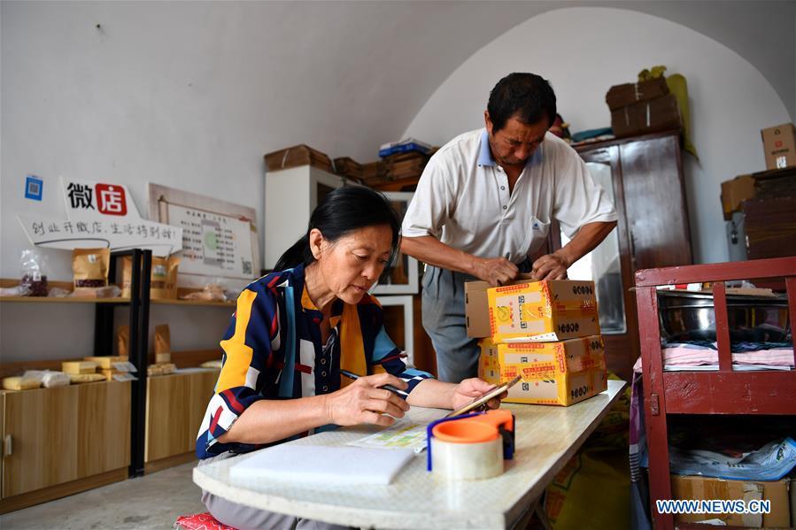 Guo Jinping (L) fills in the waybill while her husband Wei Guo packs the goods in Lingtou Village of Wuxiang County, north China\'s Shanxi Province, July 3, 2018. Online business helped villagers sell their farm products, significantly increasing the average incomes of local residents in Lingtou Village. (Xinhua/Zhan Yan)