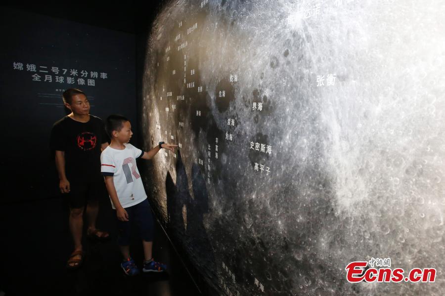 Visitors take photos of a huge moon model during an exhibition on moon held at the National Aquatic Center or \