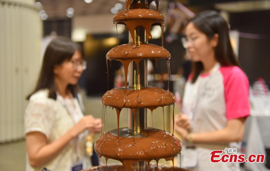 Visitors look at chocolate creations at the first Salon du Chocolat in Hong Kong, July 6, 2018. Salon du Chocolat, one of the world’s biggest chocolate events, showcases chocolate sculptures inspired by Hong Kong culture and the Year of the Dog. Meanwhile, guests were also able to sample award-winning creations during a live pastry show. (Photo: China News Service/Zhang Wei)