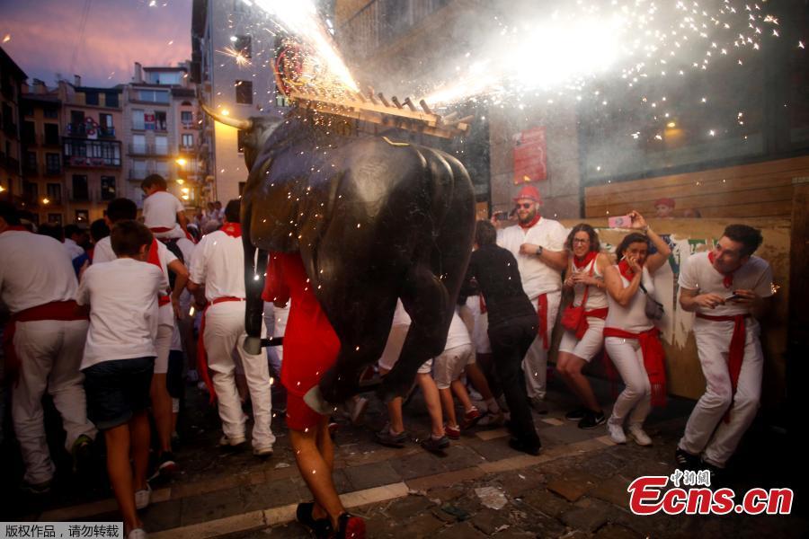 Revelers run from the Fire Bull, a man carrying a bull figure packed with fireworks, at the San Fermin festival in Pamplona, Spain July 8, 2018. (Photo/Agencies)