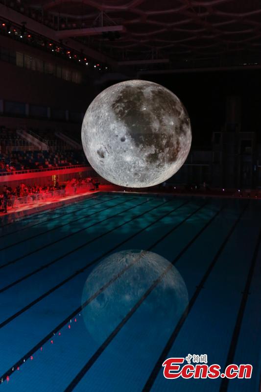 Visitors take photos of a huge moon model during an exhibition on moon held at the National Aquatic Center or \