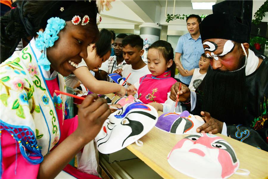Foreign students paint Peking Opera masks with children in Zhenjiang city, Jiangsu Province, on July 9, 2018.  (Photo/Asianewsphoto)
