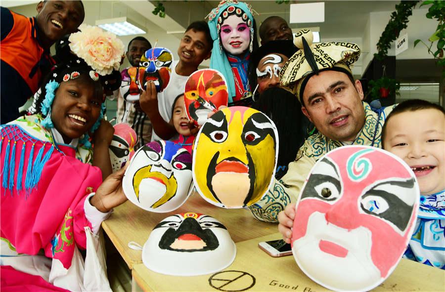 Foreign students and children show Peking Opera masks they painted in Zhenjiang city, Jiangsu Province, on July 9, 2018.  (Photo/Asianewsphoto)