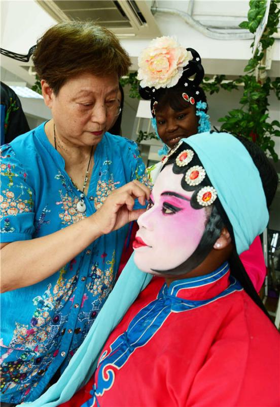A teacher applies facial makeup to a foreign student in Zhenjiang city, Jiangsu Province, on July 9, 2018.  (Photo/Asianewsphoto)