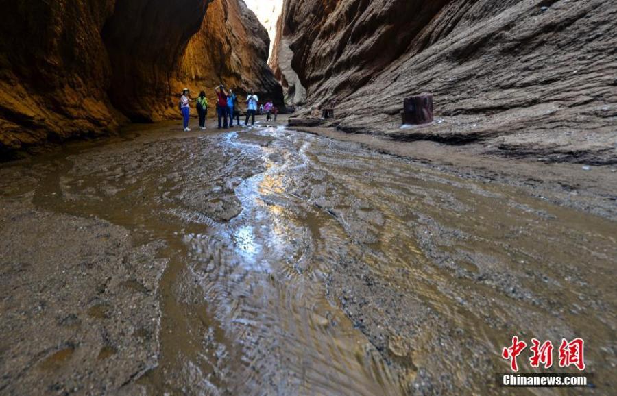 Visitors look at Kuqa Gorge, located to the south of Tianshan Mountain and about 60 kilometers to the north of Kuqa county in Aksu, Xinjiang Uygur Autonomous Region, July 10, 2018. Kuqa Gorge is made up of huge red mountains which are called \