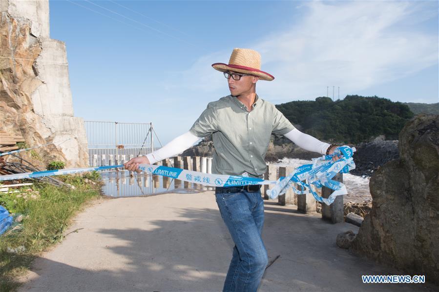 A staff member lines up cordon tape for precaution at a harbor in Xiaguan Town of Cangnan County, east China\'s Zhejiang Province, July 10, 2018, as Typhoon Maria, the eighth typhoon this year, approaches the Chinese coast. (Xinhua/Weng Xinyang)