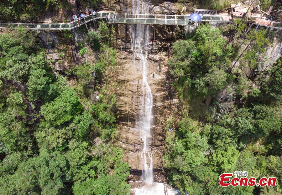 Two adventurers abseil down a 106-meter-high waterfall in Jiulong River National Park in Rucheng County, Central China’s Hunan Province, July 10, 2018. Two participants took five minutes to descend a rope from a glass walkway at the top of a cliff to the ground below. (Photo: China News Service/Yang Huafeng)