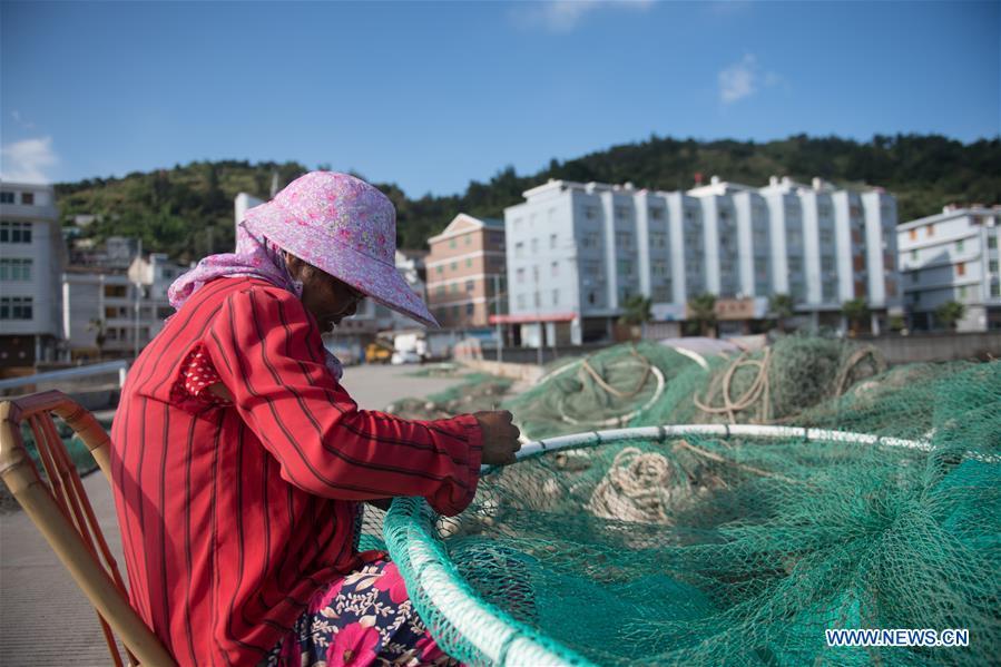 A fisherman mends fishing nets at a harbor in Xiaguan Town of Cangnan County, east China\'s Zhejiang Province, July 10, 2018, as Typhoon Maria, the eighth typhoon this year, approaches the Chinese coast. (Xinhua/Weng Xinyang)