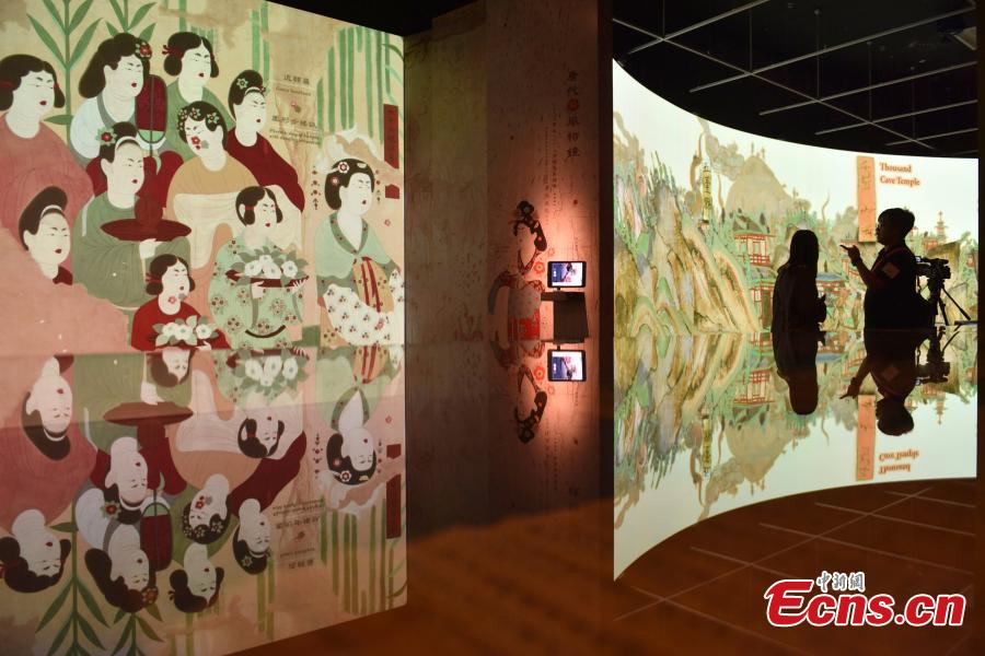 Visitors look at the Digital Dunhuang - Tales of Heaven and Earth exhibition at the Hong Kong Heritage Museum, July 10, 2018. Jointly presented by the Hong Kong Leisure and Cultural Services Department and the Dunhuang Academy, the exhibition highlights the achievements of digitization projects at the Dunhuang Academy, together with a presentation of unearthed artefacts, the grotto art of Dunhuang, and the latest multimedia technology. The Dunhuang Academy has made substantial achievements in digitization, 3D scanning and virtual reality representation of the Dunhuang relics. (Photo: China News Service/Zhang Wei)