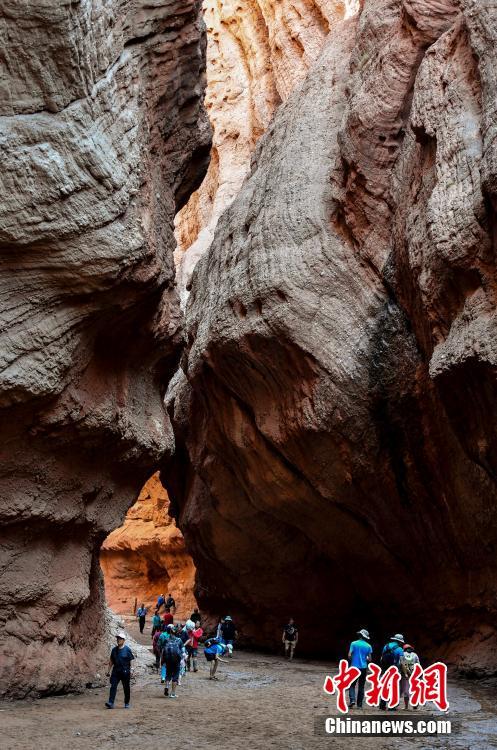Visitors look at Kuqa Gorge, located to the south of Tianshan Mountain and about 60 kilometers to the north of Kuqa county in Aksu, Xinjiang Uygur Autonomous Region, July 10, 2018. Kuqa Gorge is made up of huge red mountains which are called \