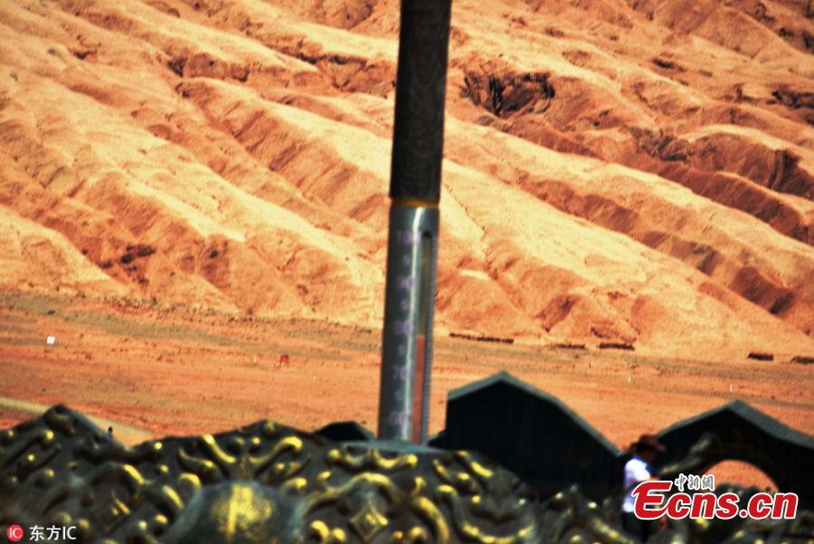 A giant thermometer records ground surface temperature of nearly 80 degrees centigrade at the Flame Mountain Scenic Area in Turpan, Xinjiang Uygur Autonomous Region, July 10, 2018. More than 2,000 tourists a day flocked to the scenic area, 40 kilometers away from downtown Turpan, to challenge the extreme heat. (Photo/IC)
