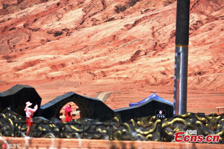 A giant thermometer records ground surface temperature of nearly 80 degrees centigrade at the Flame Mountain Scenic Area in Turpan, Xinjiang Uygur Autonomous Region, July 10, 2018. More than 2,000 tourists a day flocked to the scenic area, 40 kilometers away from downtown Turpan, to challenge the extreme heat. (Photo/IC)