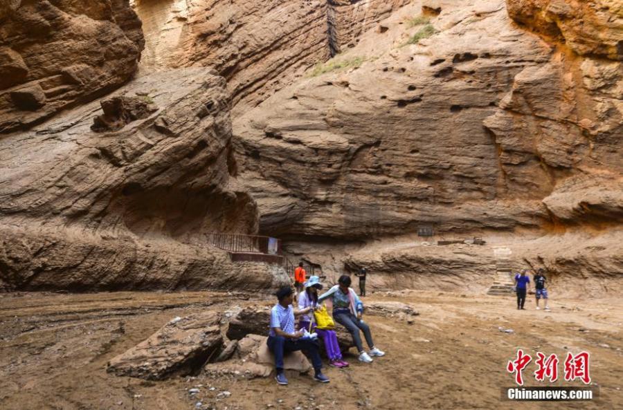 Visitors look at Kuqa Gorge, located to the south of Tianshan Mountain and about 60 kilometers to the north of Kuqa county in Aksu, Xinjiang Uygur Autonomous Region, July 10, 2018. Kuqa Gorge is made up of huge red mountains which are called \