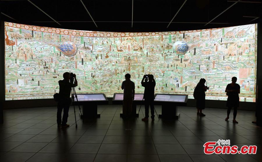 Visitors look at the Digital Dunhuang - Tales of Heaven and Earth exhibition at the Hong Kong Heritage Museum, July 10, 2018. Jointly presented by the Hong Kong Leisure and Cultural Services Department and the Dunhuang Academy, the exhibition highlights the achievements of digitization projects at the Dunhuang Academy, together with a presentation of unearthed artefacts, the grotto art of Dunhuang, and the latest multimedia technology. The Dunhuang Academy has made substantial achievements in digitization, 3D scanning and virtual reality representation of the Dunhuang relics. (Photo: China News Service/Zhang Wei)