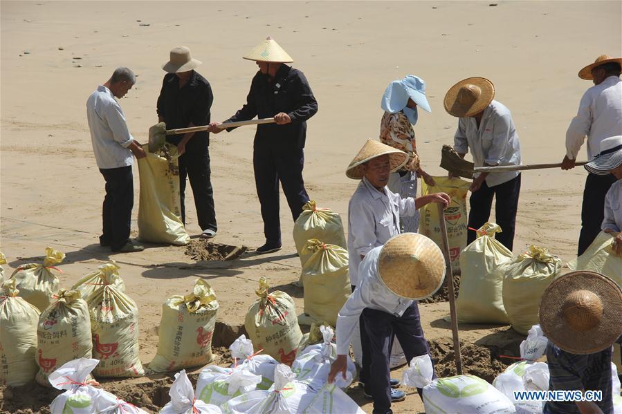 Staff workers reinforce dikes and dams with sand bags at a scenic spot in Wenling City, east China\'s Zhejiang Province, July 10, 2018. China Meteorological Administration on Tuesday issued this year\'s first red alert for typhoon as the Typhoon Maria or the 8th of the year approaches the Chinese coast. Typhoon Maria is likely to sweep Taiwan, Fujian, Jiangxi and part of Zhejiang on Tuesday and Wednesday. (Xinhua/Jin Yunguo)