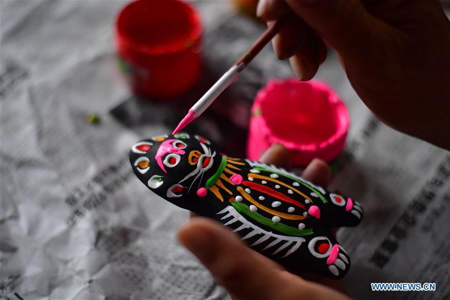 Local handicraftsman Ren Guohe paints on a clay statuette in Jinzhuang Village of Huaiyang County, central China\'s Henan Province, July 9, 2018. Originated from ancient sacrificial ceremonies, the hand-made clay statuette \