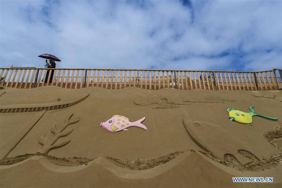 A visitor looks at a piece of sand sculpture work to be shown at the upcoming 2018 Zhoushan International Sand Sculpture Festival in Zhoushan, east China\'s Zhejiang Province, July 12, 2018. The works of over 30 sand sculptors worldwide will be officially made available to public visitors on July 21. (Xinhua/Xu Yu)
