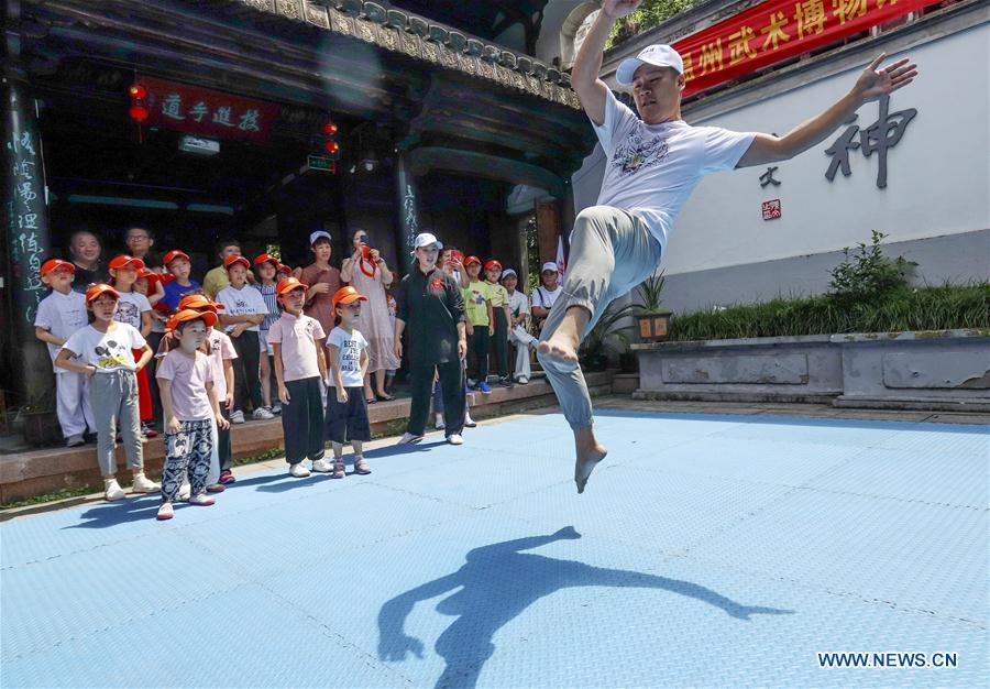 A martial arts instructor demonstrates actions for children at Wenzhou Wushu Museum in Wenzhou, east China\'s Zhejiang Province, July 14, 2018. More than 120 children visited the museum on Sunday to learn about martial arts. (Xinhua/Su Qiaojiang)