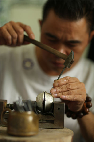 Wang demonstrates the skill of decorating silver wares in his factory, Danzhai county, Southwest China\'s Guizhou Province, July 12, 2018. (Photo//Asianewsphoto)