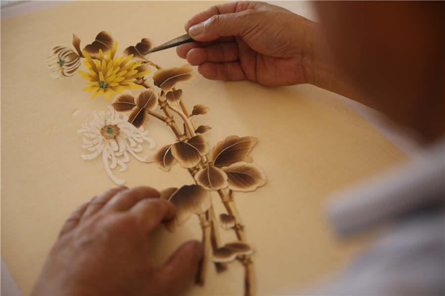 Ding Xisen pastes a straw painting on a template on July 15, 2018.  (Photo/Asianewsphoto)

Local farmer Ding Xisen in Boli town of Shandong province\'s Qingdao has dedicated more than 20 years to the study and craft of straw painting. Ding, an intangible cultural heritage inheritor, uses the natural gloss and texture quality of wheat straw to fuse the art forms of traditional Chinese painting, block print, pyrograph, paper-cutting and calligraphy into his creations.

After going through the complicated process of fuming and steaming, painting, scraping, cutting, carving, scalding, bleaching, pasting and polishing, deserted wheat straws become delicate handicrafts.