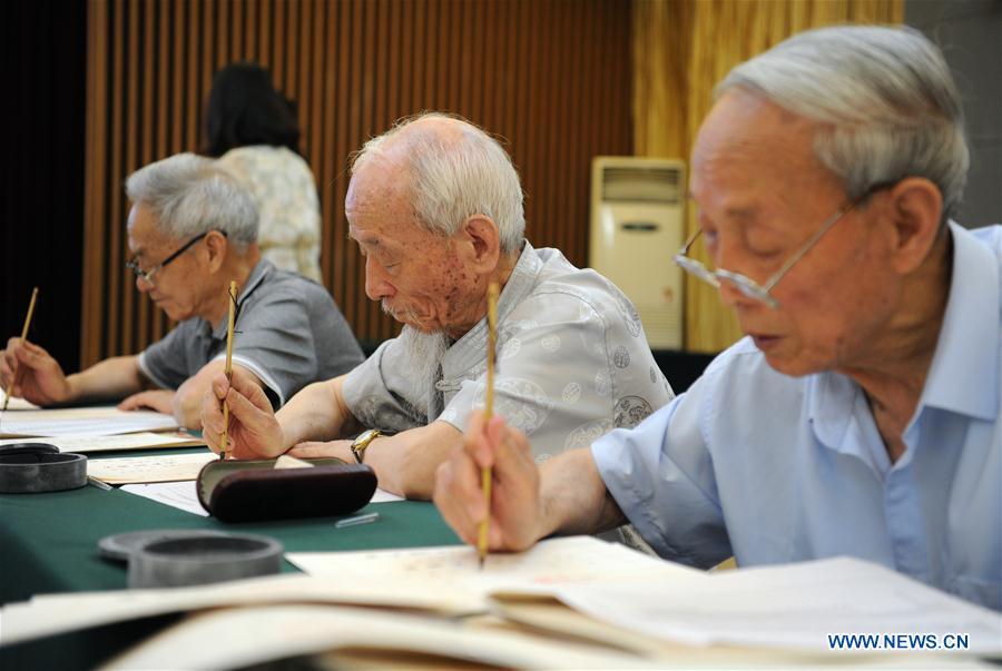 Wu Yaohui (2nd R), a retired teacher from Shaanxi Normal University, writes an admission letter with Chinese writing brush in Xi\'an, northwest China\'s Shaanxi Province, July 16, 2018. Around 4,500 admission letters written by representatives of alumni and retired teachers from Shaanxi Normal University will be delivered to freshmen. The hand-written admission letter has become a feature of Shaanxi Normal University since 2007. (Xinhua/Zhang Bowen)