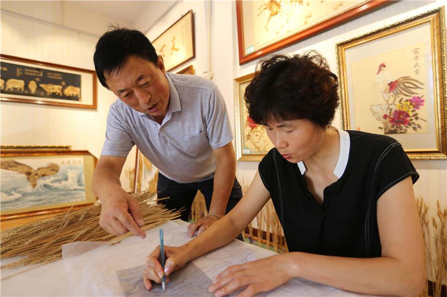 Local farmer Xu Xiufeng paints on a template under the guidance of Ding Xisen. (Photo/Asianewsphoto)