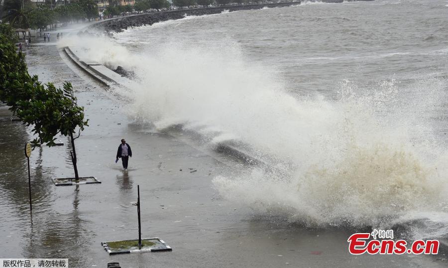 A man rides his bicycle as a wave crashes during high tide at a sea front in Mumbai, India, July 13, 2018. (Photo/Agencies)