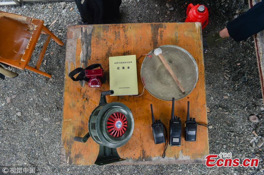 Mou Huaiqing, 65, shows his work equipment including a flashlight and an alarm apparatus in Dujiangyan City, Southwest China’s Sichuan Province. For the past nine years, since the deadly May 12 earthquake in 2008, Mou and his colleagues have been responsible for 24-hour monitoring of the valley from May to October for signs of potential landslides that could pose a threat to local villagers. They check for any cracks on mountain slopes, for example. Mou helped evacuate 300 residents and tourists in a timely manner as he sounded an alarm to warn of a landslide in August 2010. The team has sounded warnings for a dozen geological hazards. (Photo/VCG)