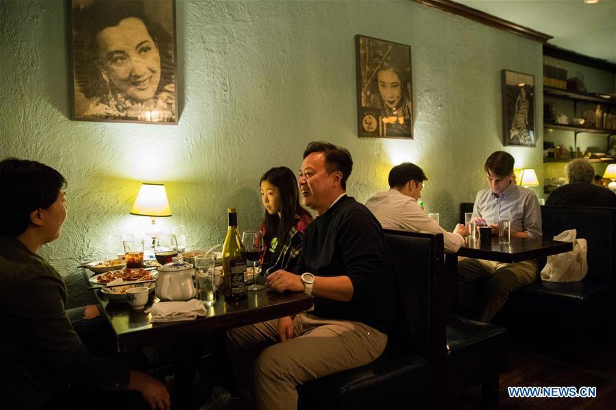 Customers have dinner at Cafe China in New York, the United States, on June 27, 2018. Walking in the bustling street of midtown Manhattan, you may not notice Cafe China if there weren\'t so many people waiting for seats outside the Chinese restaurant. Although the space is limited and decoration not so luxury, Cafe China has won Michelin one star for six consecutive years from 2012 to 2017. Wang Yiming and Zhang Xian, a couple from China, quit their well-paid financial jobs in New York and opened Cafe China with the ambition to provide authentic Sichuan food along with a comfortable dining environment. They decided not to sell American-Chinese dishes like most Chinese restaurants did at that time. Meanwhile, the couple decorated the place with items such as vintage posters, antique cameras and lamps to create an old Shanghai style. At the beginning, their idea was strongly opposed by many friends and even their staff, as the American-Chinese food was the easiest way to make money at that time. However, it surprised them that many Americans swarmed to Cafe China with curiosity for decent Chinese dishes and the unique dining environment as soon as the restaurant just opened. The couple believed the success of Cafe China resulted from not only the appeal of authentic Chinese food but also the sophisticated Chinese culture behind it. \