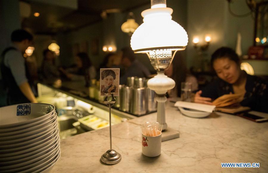 A business card is seen on the bar at Cafe China in New York, the United States, on June 27, 2018. Walking in the bustling street of midtown Manhattan, you may not notice Cafe China if there weren\'t so many people waiting for seats outside the Chinese restaurant. Although the space is limited and decoration not so luxury, Cafe China has won Michelin one star for six consecutive years from 2012 to 2017. Wang Yiming and Zhang Xian, a couple from China, quit their well-paid financial jobs in New York and opened Cafe China with the ambition to provide authentic Sichuan cuisine along with a comfortable dining environment. They decided not to sell American-Chinese dishes like most Chinese restaurants did at that time. Meanwhile, the couple decorated the place with items such as vintage posters, antique cameras and lamps to create an old Shanghai style. At the beginning, their idea was strongly opposed by many friends and even their staff, as the American-Chinese food was the easiest way to make money at that time. However, it surprised them that many Americans swarmed to Cafe China with curiosity for decent Chinese dishes and the unique dining environment as soon as the restaurant just opened. The couple believed the success of Cafe China resulted from not only the appeal of authentic Chinese food but also the sophisticated Chinese culture behind it. \
