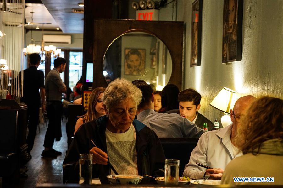 Customers have dinner at Cafe China in New York, the United States, on June 27, 2018. Walking in the bustling street of midtown Manhattan, you may not notice Cafe China if there weren\'t so many people waiting for seats outside the Chinese restaurant. Although the space is limited and decoration not so luxury, Cafe China has won Michelin one star for six consecutive years from 2012 to 2017. Wang Yiming and Zhang Xian, a couple from China, quit their well-paid financial jobs in New York and opened Cafe China with the ambition to provide authentic Sichuan cuisine along with a comfortable dining environment. They decided not to sell American-Chinese dishes like most Chinese restaurants did at that time. Meanwhile, the couple decorated the place with items such as vintage posters, antique cameras and lamps to create an old Shanghai style. At the beginning, their idea was strongly opposed by many friends and even their staff, as the American-Chinese food was the easiest way to make money at that time. However, it surprised them that many Americans swarmed to Cafe China with curiosity for decent Chinese dishes and the unique dining environment as soon as the restaurant just opened. The couple believed the success of Cafe China resulted from not only the appeal of authentic Chinese food but also the sophisticated Chinese culture behind it. \