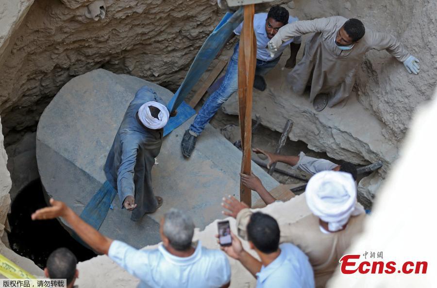 Archaeologists and workers stand over a coffin containing three mummies in Alexandria, Egypt July 19, 2018. (Photo/Agencies)