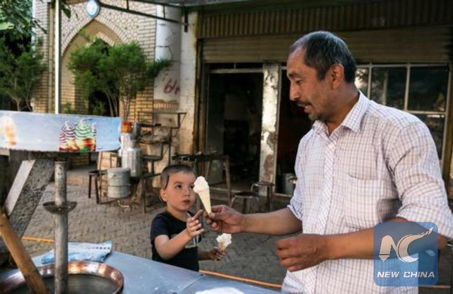 A little boy reaches eagerly for his second cone from an ice cream vendor in Kashgar on May 20. (Photo: Xinhua/Zhao Ge)
Nothing says summer quite like the taste of fresh, in-season produce. And a walk through the winding streets of Kashgar\'s old city is a feast for the senses: the air fragrant with ripe, juicy melons, and fresh tea, and the streets alive with the sound of stall owners hawking their wares.
There has been a settlement on the site of modern-day Kashgar for over 2,000 years. The trading hub was once an outpost on the ancient Silk Road, offering respite for weary travelers as they moved between China, the Middle East and Europe. Its commerce roots run deep and continue to this day. In 2010, the city was made into a Special Economic Zone, the only city in western China with such distinction.
The city is more than a tourist destination, however, and more and more people are moving to Kashgar, drawn to the dynamic, promising business environment.