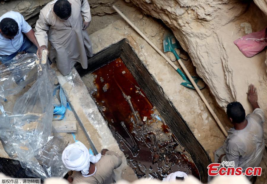Archaeologists and workers stand over a coffin containing three mummies in Alexandria, Egypt July 19, 2018. (Photo/Agencies)