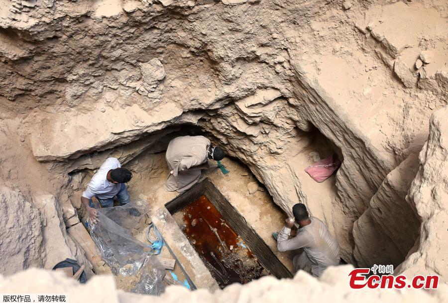 Archaeologists and workers stand over a coffin containing three mummies in Alexandria, Egypt July 19, 2018. (Photo/Agencies)