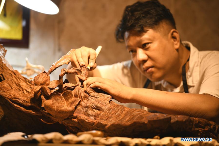 Craftsman Guo Dong makes wood carvings at a studio in Shijiazhuang, capital of north China\'s Hebei Province, July 20, 2018. The \
