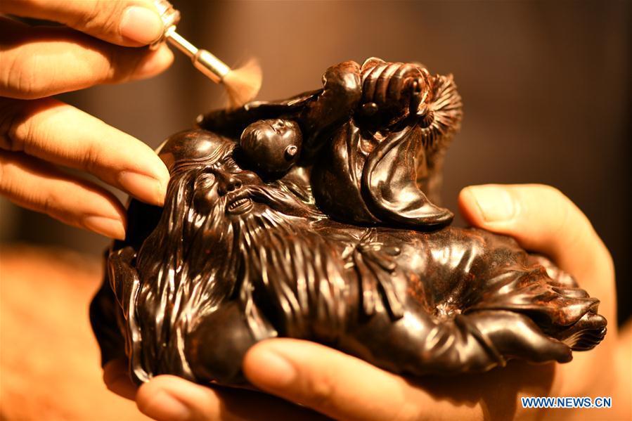 Craftsman Guo Dong makes wood carvings at a studio in Shijiazhuang, capital of north China\'s Hebei Province, July 20, 2018. The \