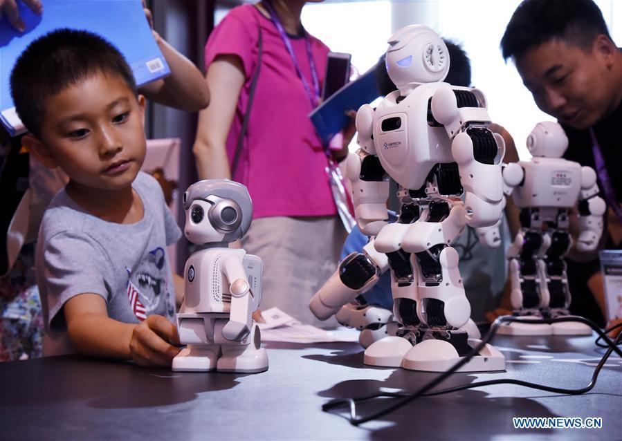 Visitors look at robots during the 2018 China International Consumer Electronics Show in Qingdao, east China\'s Shandong Province, July 21, 2018. The four-day electronics show kicked off on Friday. (Xinhua/Li Ziheng)