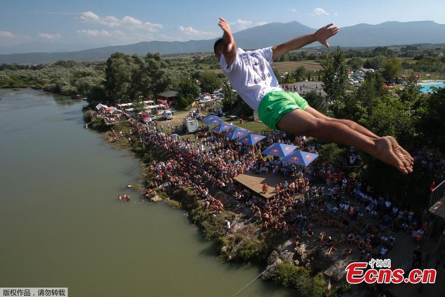 People look at a man as he jumps from the 22 meters high bridge \'Ura e Shenjte\' during the annual traditional High Diving competition near the town of Gjakova on July 22, 2018. (Photo/Agencies)