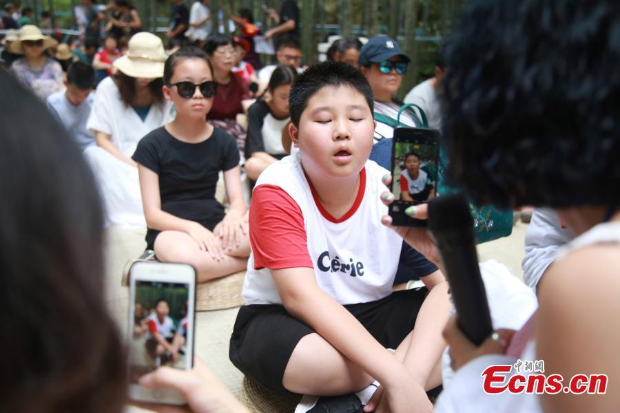 Blank-faced contestants, including children, sit still and do nothing in a “space-out” contest in Hangzhou City, the capital of East China’s Zhejiang Province, July 21, 2018. Some 100 residents attended the contest, enjoying a moment or two of relaxation. (Photo: China News Service/Liu Peiqi)