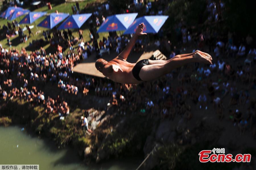 People look at a man as he jumps from the 22 meters high bridge \'Ura e Shenjte\' during the annual traditional High Diving competition near the town of Gjakova on July 22, 2018. (Photo/Agencies)