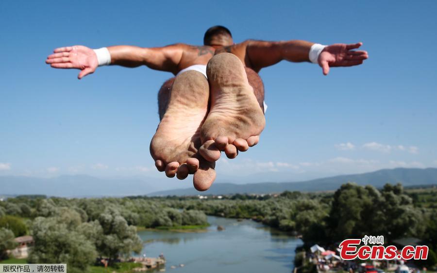 People look at a man as he jumps from the 22 meters high bridge \'Ura e Shenjte\' during the annual traditional High Diving competition near the town of Gjakova on July 22, 2018. (Photo/Agencies)