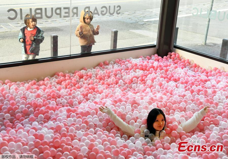 A visitor to Sugar Republic plays in a display of balls resembling lollies in Melbourne on July 24, 2018. Sugar Republic is an interactive pop-up museum dedicated to the celebration of desserts, candy and all things sweet through 12 amazing sensory rooms. (Photo/Agencies)
