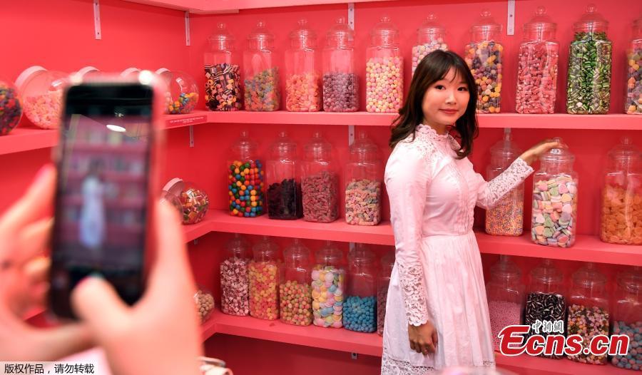 A visitor to Sugar Republic poses for a friend in a display in Melbourne on July 24, 2018. Sugar Republic is an interactive pop-up museum dedicated to the celebration of desserts, candy and all things sweet through 12 amazing sensory rooms.(Photo/Agencies)