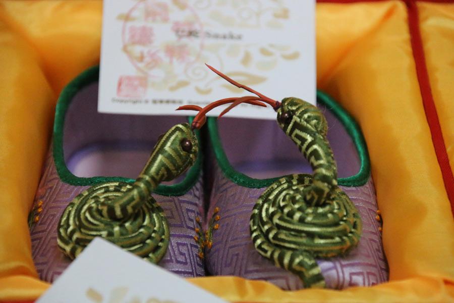 A coiled snake from the Chinese zodiac rises from the toes of a pair of embroidered shoes made by Wang Guanqin, July 21, 2018. (Photo/chinadaily.com.cn)

In 2007, Wang\'s handmade embroidered shoes and her skills were placed on Beijing\'s Intangible Cultural Heritage list. She is said to be the premier figure in Chinese embroidered shoemaking.

Her shoes have now become precious gifts for people to give for special occasions, such as at weddings or to treasure as an art piece.

The Great Seed, a global community platform aimed at all intangible cultural heritage enthusiasts to communicate, share, experience and inherit intangible cultural heritage worldwide, is now recruiting people to be participants who will learn and experience such heritage.

Through June 9, 2019, 1,000 people around the world will be recruited to connect with 1,000 inheritors to have an in-depth experience with different forms of intangible cultural heritage.