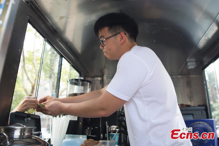 Food truck owner Fei Xiang exchanges free coffee for ten cigarette butts, picked up by customers in Flushing, New York City, U.S., July 26, 2018. Fei’s food truck offered customers free coffee in exchange for ten cigarette butts, picked up from around the community, as an initiative to improve the local environment. Fei said he delivered about five to ten cups of free coffee a day. (Photo: China News Service/Liao Pan)