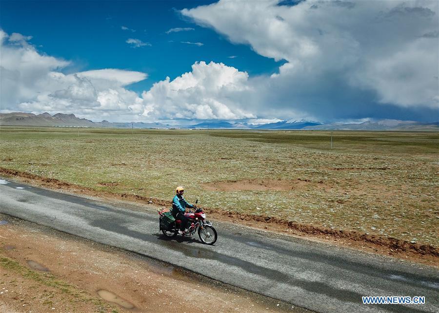 Motorbike courier Gesang Cering performs a mail delivery task in Pumaqangtang Township of Nagarze County in Shannan, southwest China\'s Tibet Autonomous Region, July 27, 2018. In Pumaqantang Township, the highest township in China, working as a postal service staff means delivering mails to addresses at altitudes of 5,000 meters and above. Gesang Cering, 29, is a motorbike courier with the local township branch of China Post. Twice a week, Gesang calls on the plateau villages under the township on a 160-km route, coping with extreme oxygen and temperature conditions. Despite its harsh geography, Tibet Autonomous Region has substantially improved the local postal service over the four decades since China\'s reform and opening up. By the end of 2017, the postal road network had managed to cover all towns and counties within the autonomous region. (Xinhua/Li He)