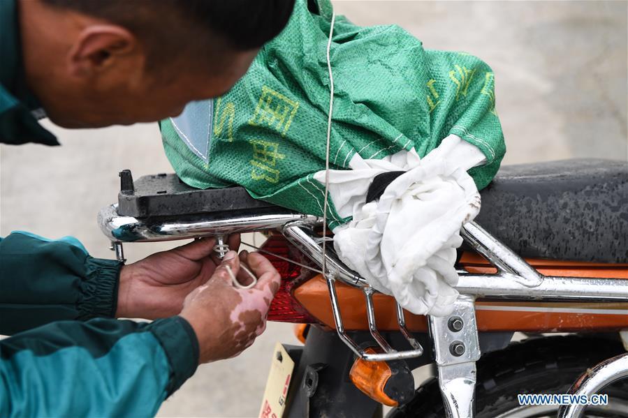 Motorbike courier Gesang Cering fixes a postal mail bag to the rear of his motorbike before setting off for work in Pumaqangtang Township of Nagarze County in Shannan, southwest China\'s Tibet Autonomous Region, July 23, 2018. In Pumaqantang Township, the highest township in China, working as a postal service staff means delivering mails to addresses at altitudes of 5,000 meters and above. Gesang Cering, 29, is a motorbike courier with the local township branch of China Post. Twice a week, Gesang calls on the plateau villages under the township on a 160-km route, coping with extreme oxygen and temperature conditions. Despite its harsh geography, Tibet Autonomous Region has substantially improved the local postal service over the four decades since China\'s reform and opening up. By the end of 2017, the postal road network had managed to cover all towns and counties within the autonomous region. (Xinhua/Li He)