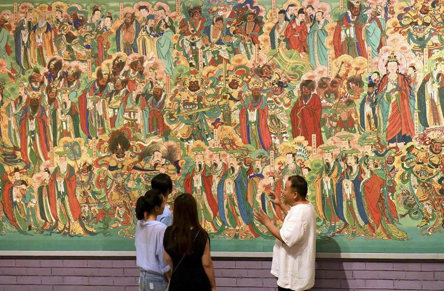 Yao Shulong introduces visitors at the Hebei Museum to the murals of Pilu Temple through his replica works on July 25, 2018. (Photo/Xinhua)