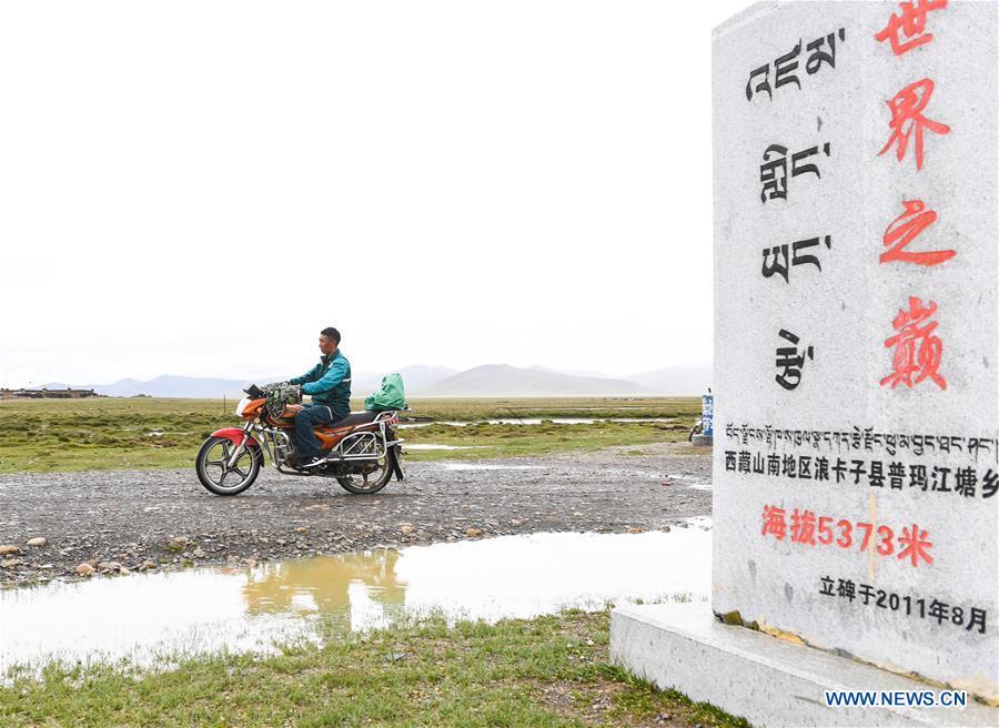 Motorbike courier Gesang Cering performs a mail delivery task in Pumaqangtang Township of Nagarze County in Shannan, southwest China\'s Tibet Autonomous Region, July 23, 2018. In Pumaqantang Township, the highest township in China, working as a postal service staff means delivering mails to addresses at altitudes of 5,000 meters and above. Gesang Cering, 29, is a motorbike courier with the local township branch of China Post. Twice a week, Gesang calls on the plateau villages under the township on a 160-km route, coping with extreme oxygen and temperature conditions. Despite its harsh geography, Tibet Autonomous Region has substantially improved the local postal service over the four decades since China\'s reform and opening up. By the end of 2017, the postal road network had managed to cover all towns and counties within the autonomous region. (Xinhua/Li He)